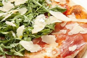 pizza med parmesanost, rucola och prosciutto närbild foto