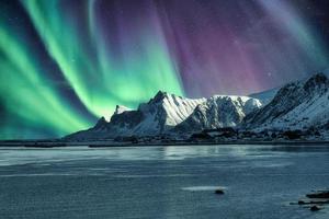 aurora borealis, norrsken ovanför snöiga berg på lofoten öar foto