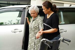 vårdgivare hjälpa asiatisk äldre kvinna funktionshinder patient få i sin bil, medicinsk koncept. foto