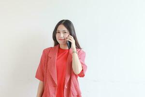 porträtt av skön asiatisk kvinna bär röd utrusta medan kallelse med leende uttryck foto