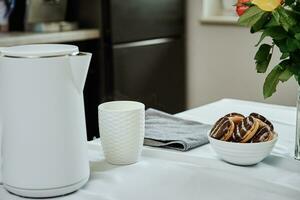 elektrisk vattenkokare och kopp för te på tabell foto