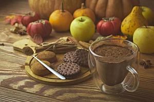 varm kakao, kakor och höstskörd på träbord. foto