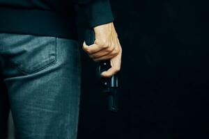 mannen i mörka kläder håller pistolen. foto