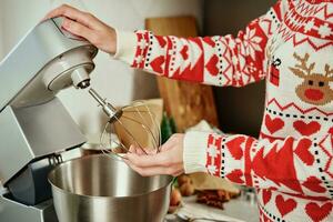 kvinna matlagning på Hem kök, använda sig av elektrisk mixer till framställning deg foto