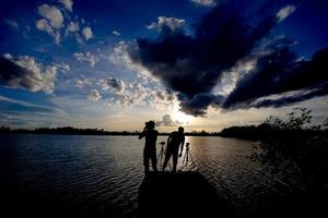 silhuett av två man på floden under solnedgången foto