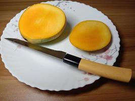 skivad mango med kniv på tallriken foto