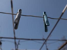 två klädnypor som hänger på ett rep på gatan mot en blå himmel foto