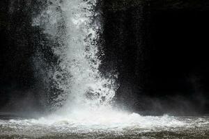 stänk vatten från kraftfull vattenfall med mörk bakgrund. foto