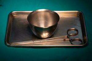 kirurgisk instrument i silver- bricka på grön tabell foto