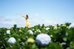 glad asiatisk kvinna håller handen i ett fält av hortensiablommor