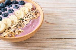 yoghurt eller smoothieskål med blåbär, banan och granola - hälsosam matstil foto