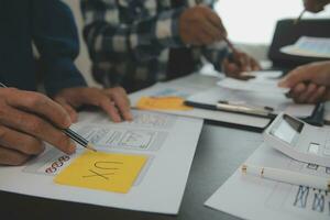 stänga upp ux utvecklare och ui designer brainstorming handla om mobil app gränssnitt trådmodell design på tabell med kund kortfattat och Färg koda på modern office.creative digital utveckling byrå foto