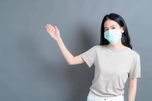 asiatisk kvinna som bär medicinsk ansiktsmask skyddar filterdamm pm2.5 anti-förorening, anti-smog och covid-19 med handpresenterande foto