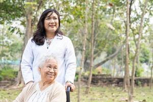 asiatisk senior eller äldre gammal damkvinnapatient med vård, hjälp och stöd på rullstol i park i semestern, hälsosamt starkt medicinskt koncept. foto