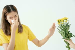 pollen allergier, asiatisk ung kvinna nysning i en näsduk eller blåser i en torka, allergisk till vild vår blommor eller blommar under vår. allergisk reaktion, respiratorisk systemet problem foto