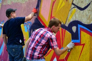 Kharkov, ukraina - Maj 27, 2017 festival av gata konst. ung grabbar dra graffiti på bärbar trä- väggar i de Centrum av de stad. de bearbeta av målning på väggar med aerosol spray burkar foto