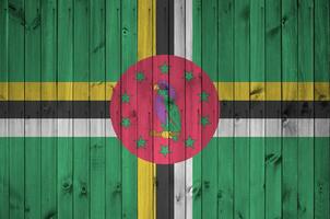 dominica flagga avbildad i ljus måla färger på gammal trä- vägg. texturerad baner på grov bakgrund foto