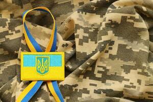 militär kamouflage tyg med ukrainska flagga på enhetlig sparre foto