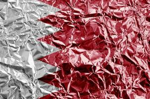 bahrain flagga avbildad i måla färger på skinande skrynkliga aluminium folie närbild. texturerad baner på grov bakgrund foto