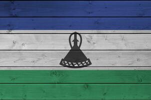 lesotho flagga avbildad i ljus måla färger på gammal trä- vägg. texturerad baner på grov bakgrund foto