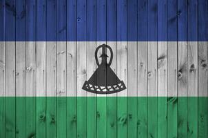 lesotho flagga avbildad i ljus måla färger på gammal trä- vägg. texturerad baner på grov bakgrund foto