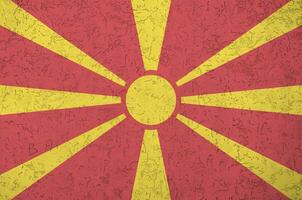 macedonia flagga avbildad i ljus måla färger på gammal lättnad putsning vägg. texturerad baner på grov bakgrund foto