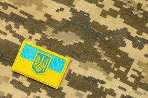 militär kamouflage tyg med ukrainska flagga på enhetlig sparre foto