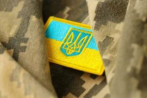 militär kamouflage tyg med ukrainska flagga på enhetlig sparre foto