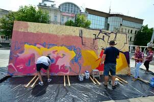 Kharkov, ukraina - Maj 27, 2017 festival av gata konst. ung grabbar dra graffiti på bärbar trä- väggar i de Centrum av de stad. de bearbeta av målning på väggar med aerosol spray burkar foto