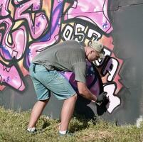 ung caucasian manlig graffiti konstnär teckning stor gata konst målning i blå och rosa toner foto