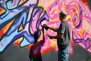 ung caucasian manlig graffiti konstnär teckning stor gata konst målning i blå och rosa toner foto