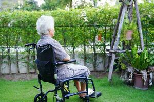 asiatisk äldre kvinna funktionshinder patient sitter på rullstol i parken, medicinsk koncept. foto