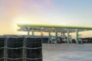 svart olja fat mot med gas station suddig bakgrund foto
