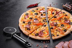 färsk utsökt pizza gjord i en härdugn med oliver, chilipeppar och skinka foto