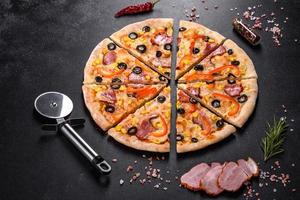 färsk utsökt pizza gjord i en härdugn med oliver, chilipeppar och skinka foto