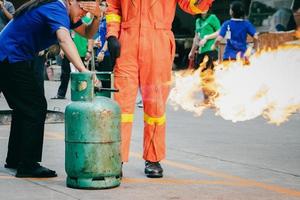 anställd brandbekämpningsträning, stäng av gasbehållarventilen som tänds. foto