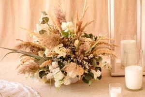 dekorationer från torra vackra blommor i en vit vas på en beige tygbakgrund