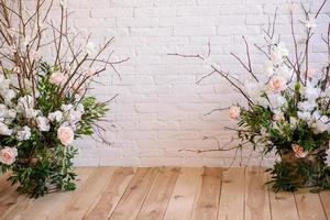 dekorationer av grenar med vackra rosa och vita blommor i korgen mot bakgrunden av en vit tegelvägg foto