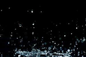 regn. vatten droppar, stänk på en svart bakgrund foto