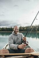 Kanada, brittiskt columbia, porträtt av Lycklig man fiske i kanot på boya sjö foto