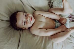 Lycklig bebis, liggande på säng, skrattande foto