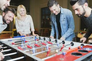 Lycklig kollegor spelar foosball i kontor foto