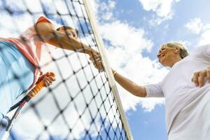 mogna kvinnor efterbehandling tennis match skakning händer på de netto foto