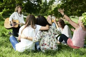 grupp av kvinnor med gitarr har roligt på en picknick i parkera foto