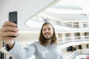 porträtt od leende man tar selfie med cell telefon foto