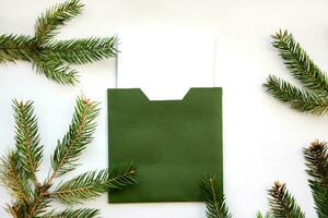 layout av en eleganta jul kort. grön kuvert på en vit bakgrund med en ram av gran grenar. jul eve. foto