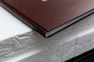 Foto bok med en omslag av äkta läder. brun Färg med dekorativ stämpling . Linné tyg bakgrund