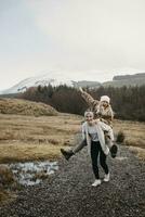 Storbritannien, Skottland, Lycklig ung kvinna bärande vän piggyback i lantlig landskap foto