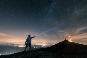 Italien, Monte nerone, silhuett av en man med ficklampa under natt himmel med stjärnor och mjölkig sätt foto