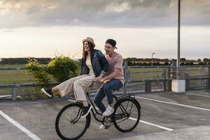 Lycklig ung par tillsammans på en cykel på parkering däck foto